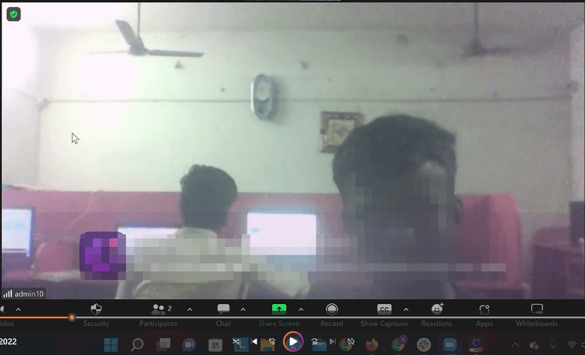 Screenshot from a CloudResearch video interview showing several men working at computers in a dimly lit room while taking online surveys