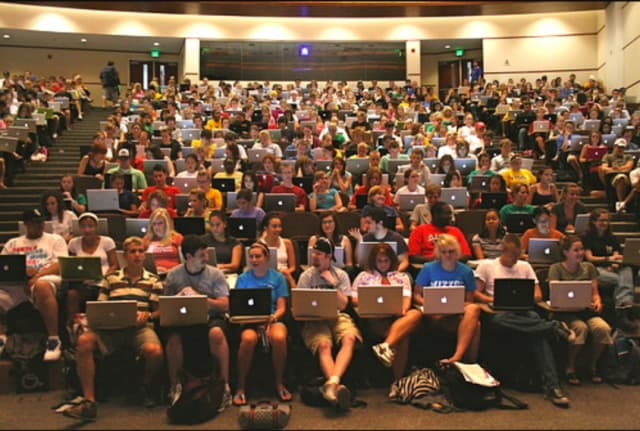 College students using MacBook laptops in a classroom