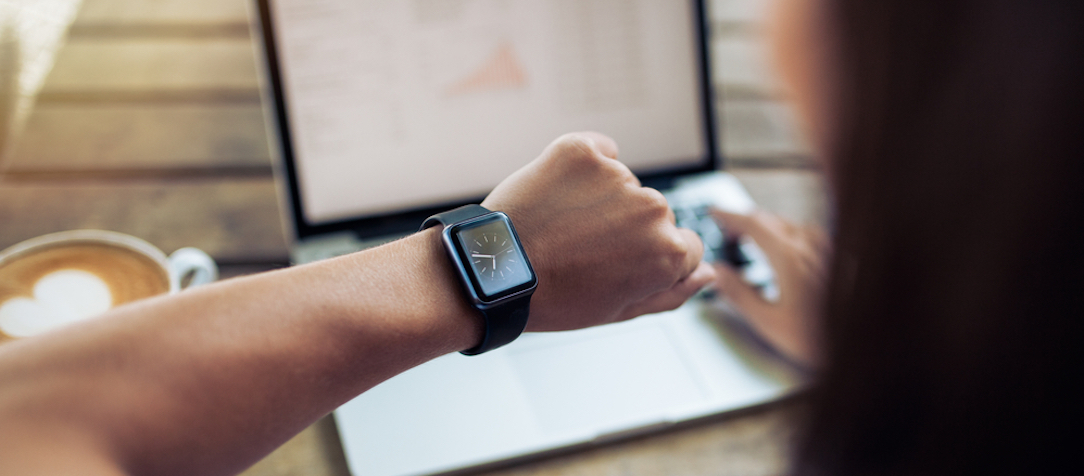 A female working at a coffee shop checks her smartwatch