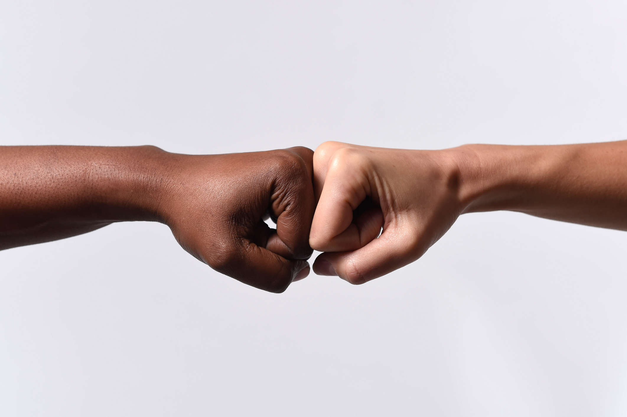 black African American race hand touching knuckles with white Caucasian